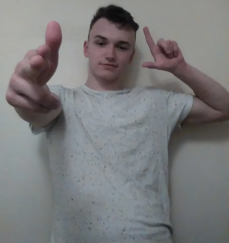 A younger Yuozas pointing double finger guns at the camera
